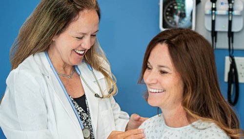 Nurse performing a checkup on a smiling patient.