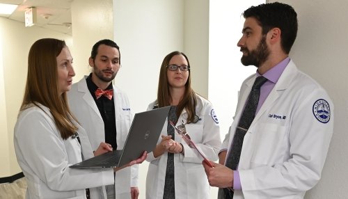 Graduate Medical Education staff discussing healthcare practices in the hallway.