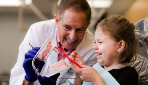 dentist showing child how to brush teeth