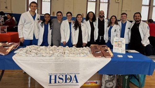 CDMI Students and Faculty stand near a table of information