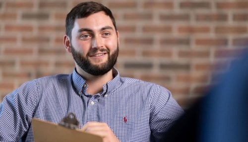 Doctor of Clinical Psychology student uses a clipboard to take notes during a counseling session.