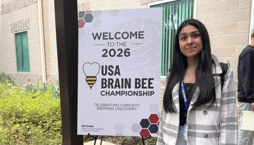 High school student Shireen Arora stands next to the USA Brain Bee sign at the competition