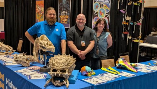 Three anatomy professors stand behind Midwestern's Fan Fusion booth, with various real and fictional skulls on the table