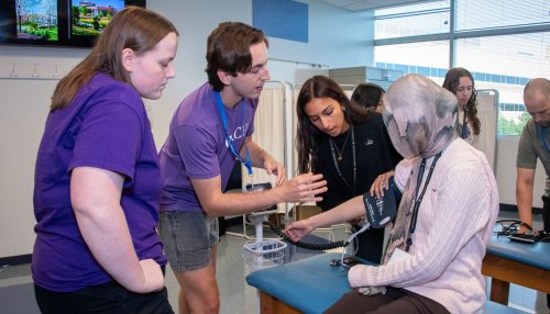 HCI mentor helps students use blood pressure cuff at the Downers Grove campus.