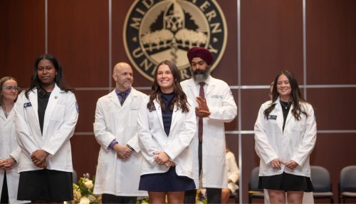 Students in the College of Health Sciences - Downers Grove receive their white coats on stage