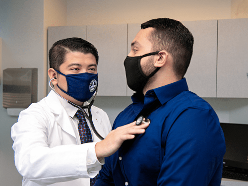 Nursing student listening to patient's lungs.