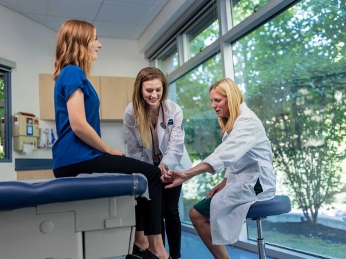 Students in the Physician Assistant program examining patient's knee.