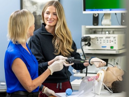 Student, teacher putting tube in mouth of mannequin
