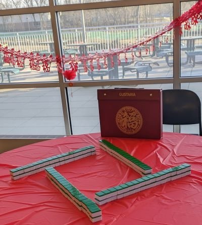 Mah Jong tiles and case displayed on a table and window decorated with red garland.