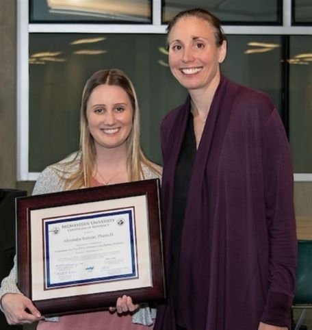 Dr. Statczar holds her residency completion certificate while standing next to Dr. Schumacher.