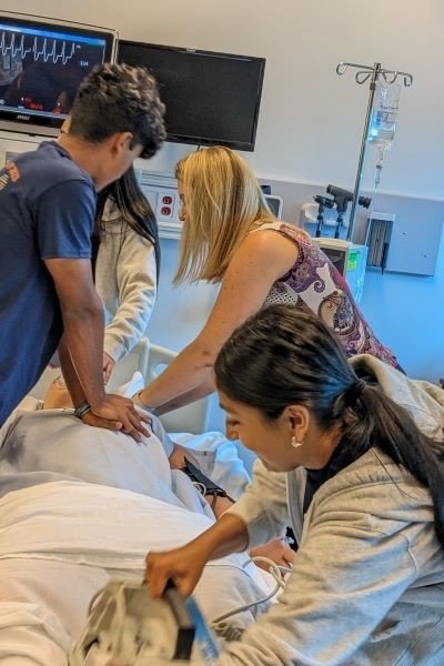 Students administer CPR to a mannikin under faculty supervision.