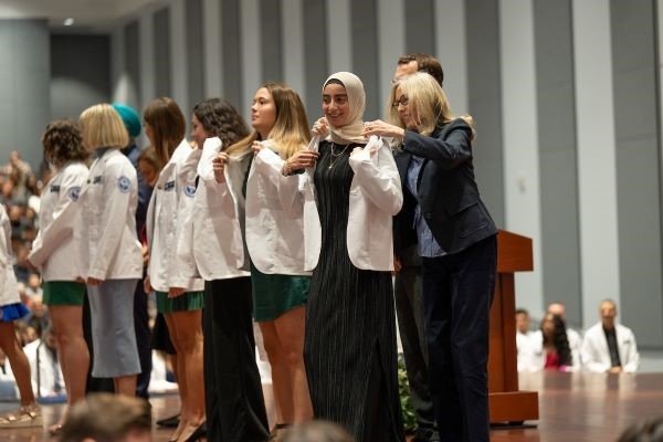 Students receive their white coats.