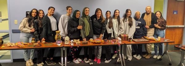Attendees gather in front of a table of Arab cultural artifacts.