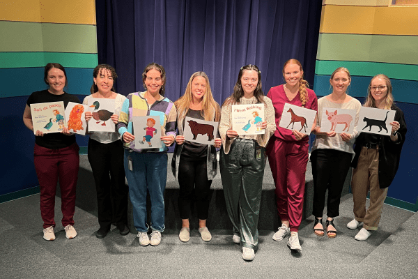 SLP students during the Family Literacy night carrying visual aids to help children read.