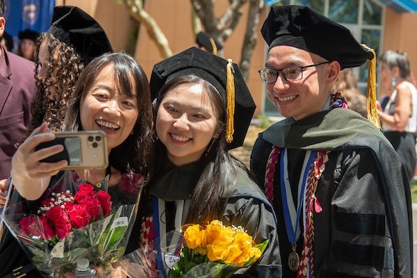 Graduates pose for a selfie with family members