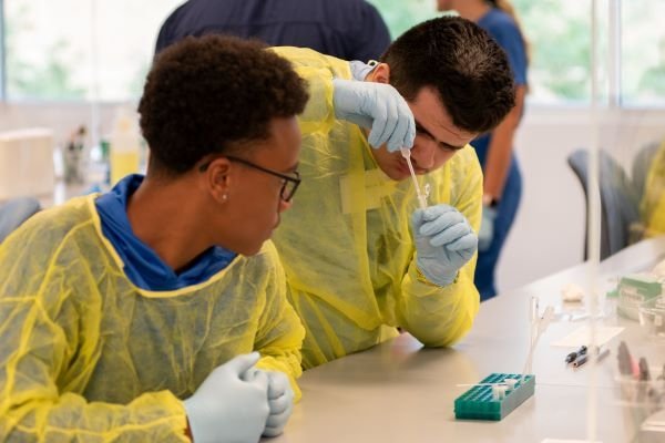 The high school students conducted Gram staining, strep throat tests, and observed specimens in the microbiology lab. 