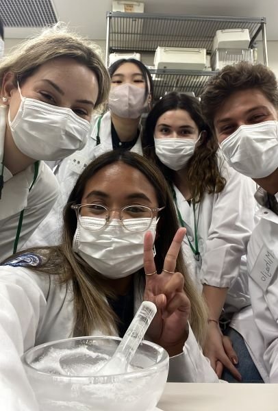 Bethany in a pharmacy lab in white coats with her cohorts.