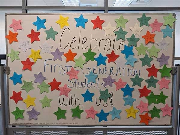 A whiteboard with the words "Celebrate First Generation Students with Us." Different colored stars are taped to a whiteboard.