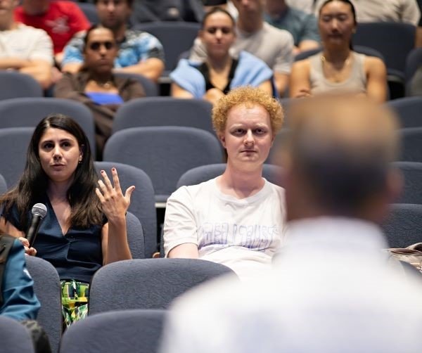 A medical student raises her hand and asks Mr. Giglio a question at the patient panel.