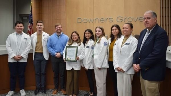 Pharmacy students in white coats, faculty with the Downers Grove Commissioner and Mayor Pro Tem Gregory Hosé.