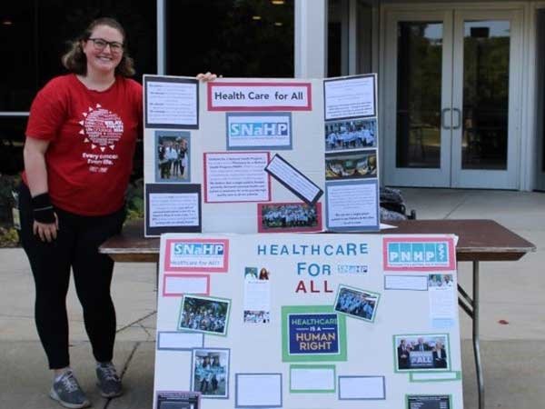 Students stands before posters of the Students for a National Health Program.