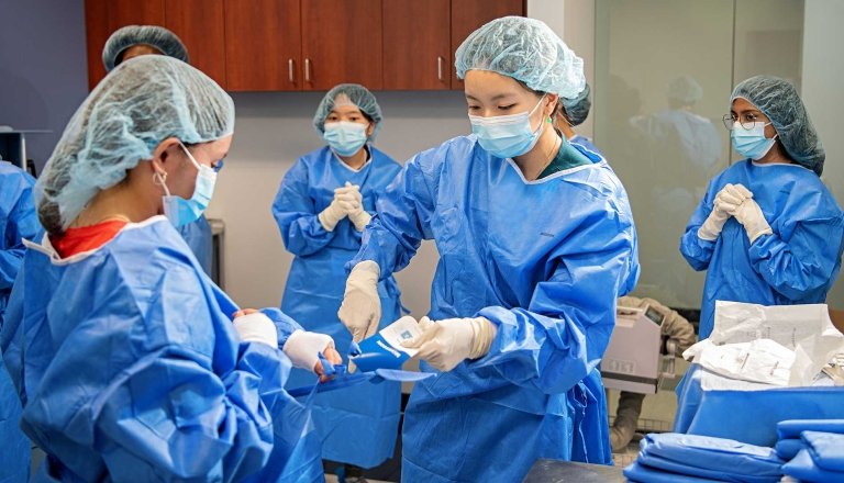 Students wear gowns and gloves at the Health Careers Institute.