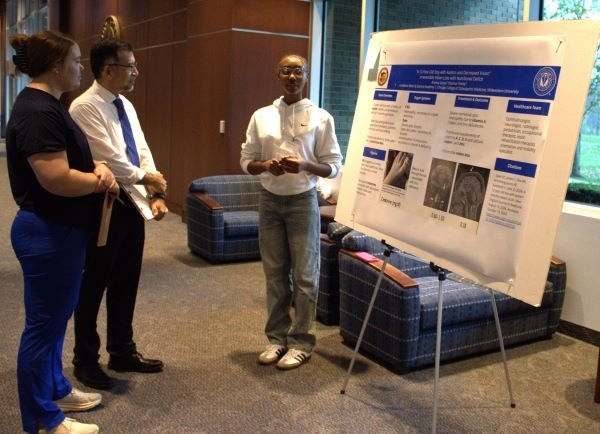 Kyle Henderson and Madeline Schnurr (CCOM ’28) listen to a case study presentation from Mini Medical School participant Adama Gueye.