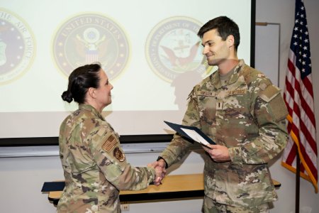Military student Jacob Thiessen shakes hands with Major Julie Brown
