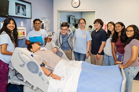 Midwestern student mentors teach the high school students to take vitals on the simulation center mannequin