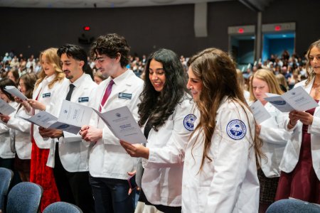 Students from the College of Health Sciences - Glendale read the Oath of Commitment in their white coats