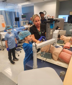 A kid learns how to intubate on a mannequin in the Nurse Anesthesia lab